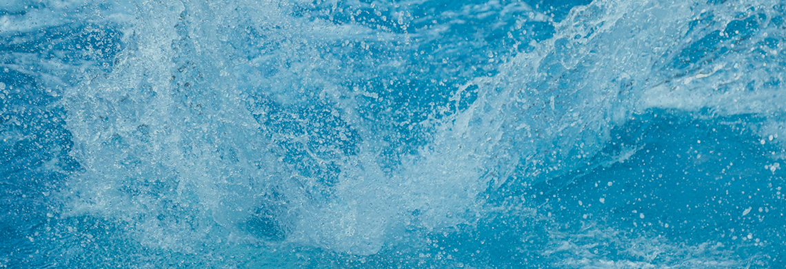 Close-up of splashing blue water with bubbles and foam filling the frame.